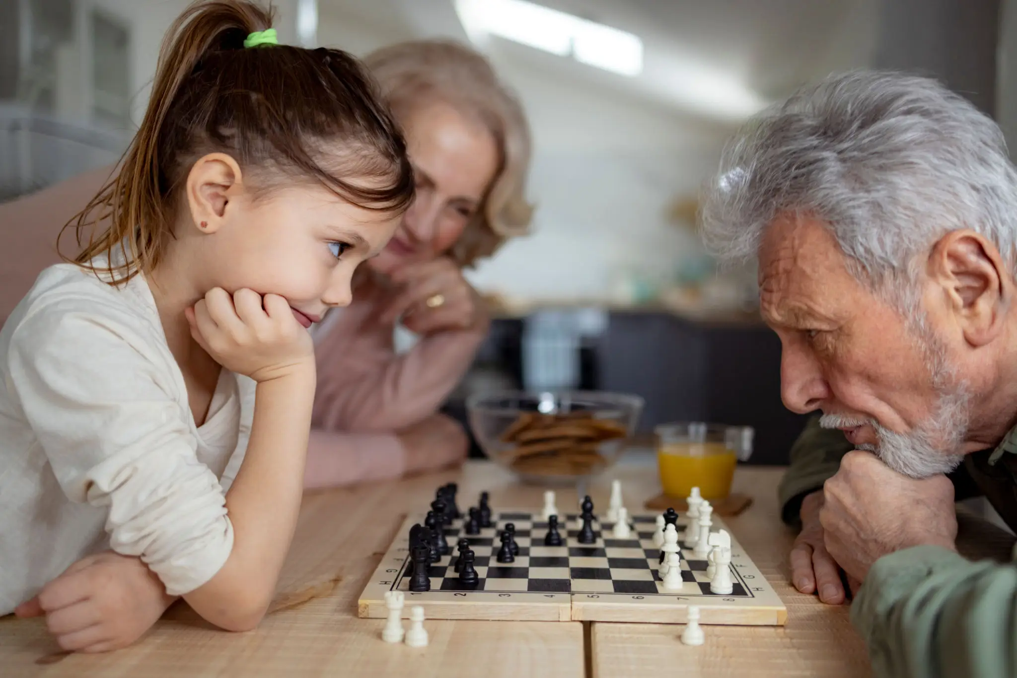 Three generations enjoying a chess game together.